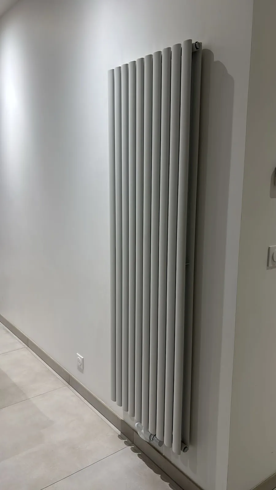 Radiateur vertical tubulaire installé dans un couloir